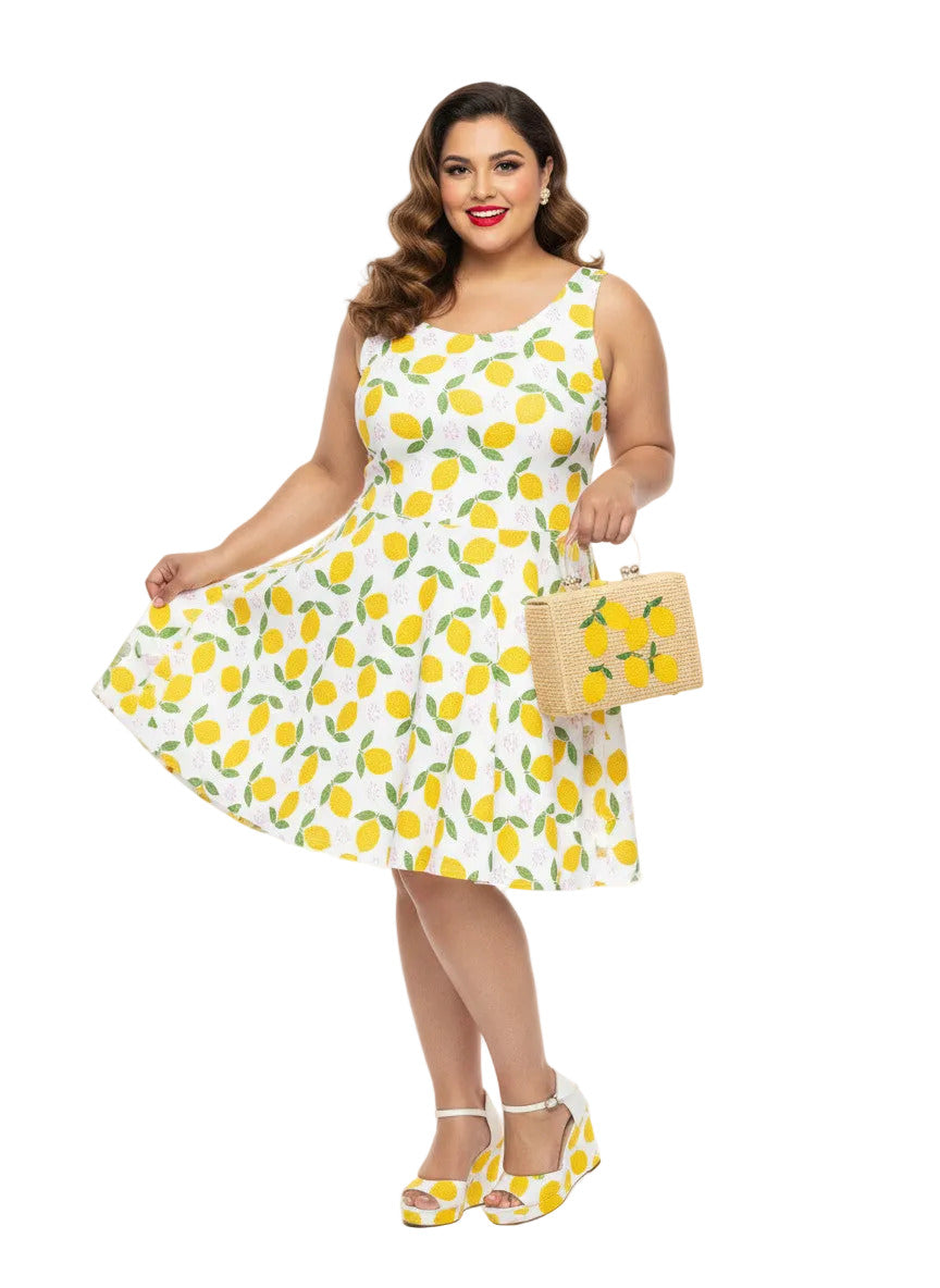 Plus size woman in a 1950s lemon print vintage swing dress with a fit and flare silhouette and yellow citrus pattern.