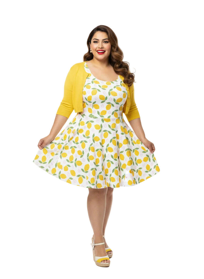 Plus size woman in a 1950s lemon print vintage swing dress with a fit and flare silhouette and yellow citrus pattern.