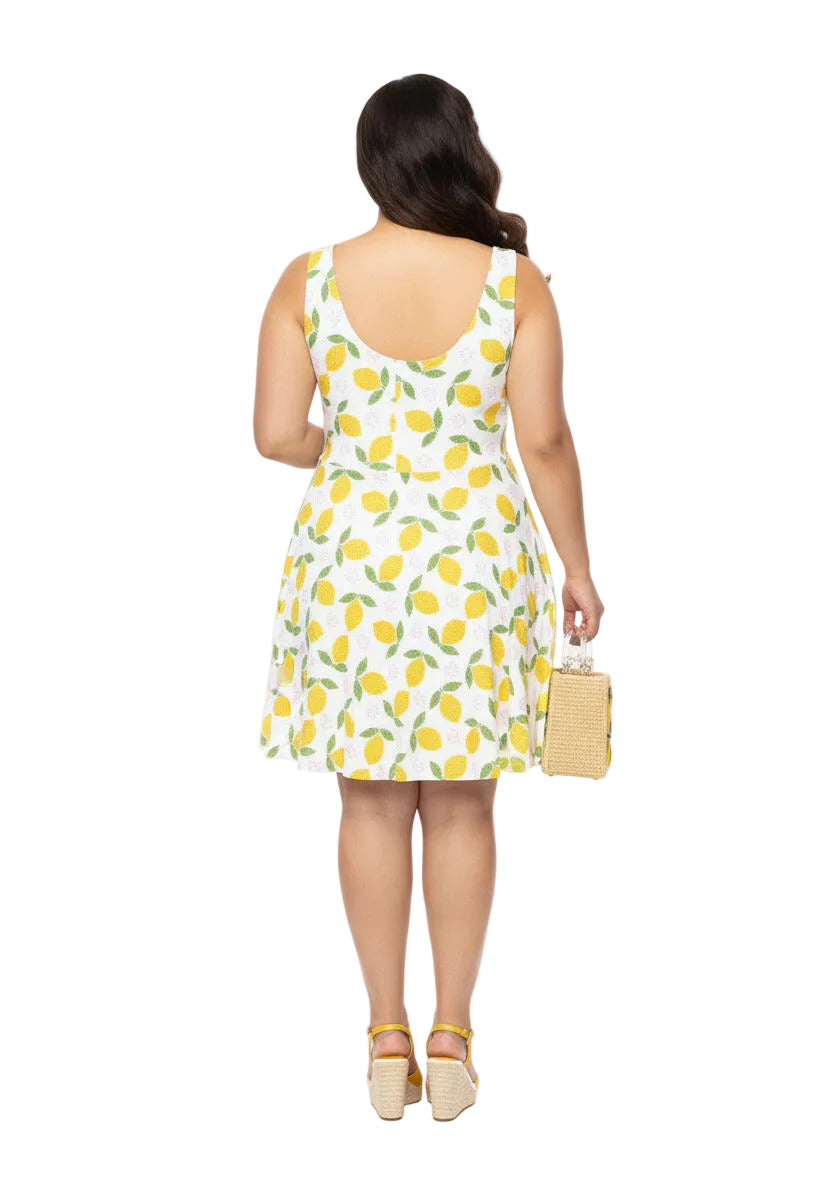 Plus size woman in a 1950s lemon print vintage swing dress with a fit and flare silhouette and yellow citrus pattern.
