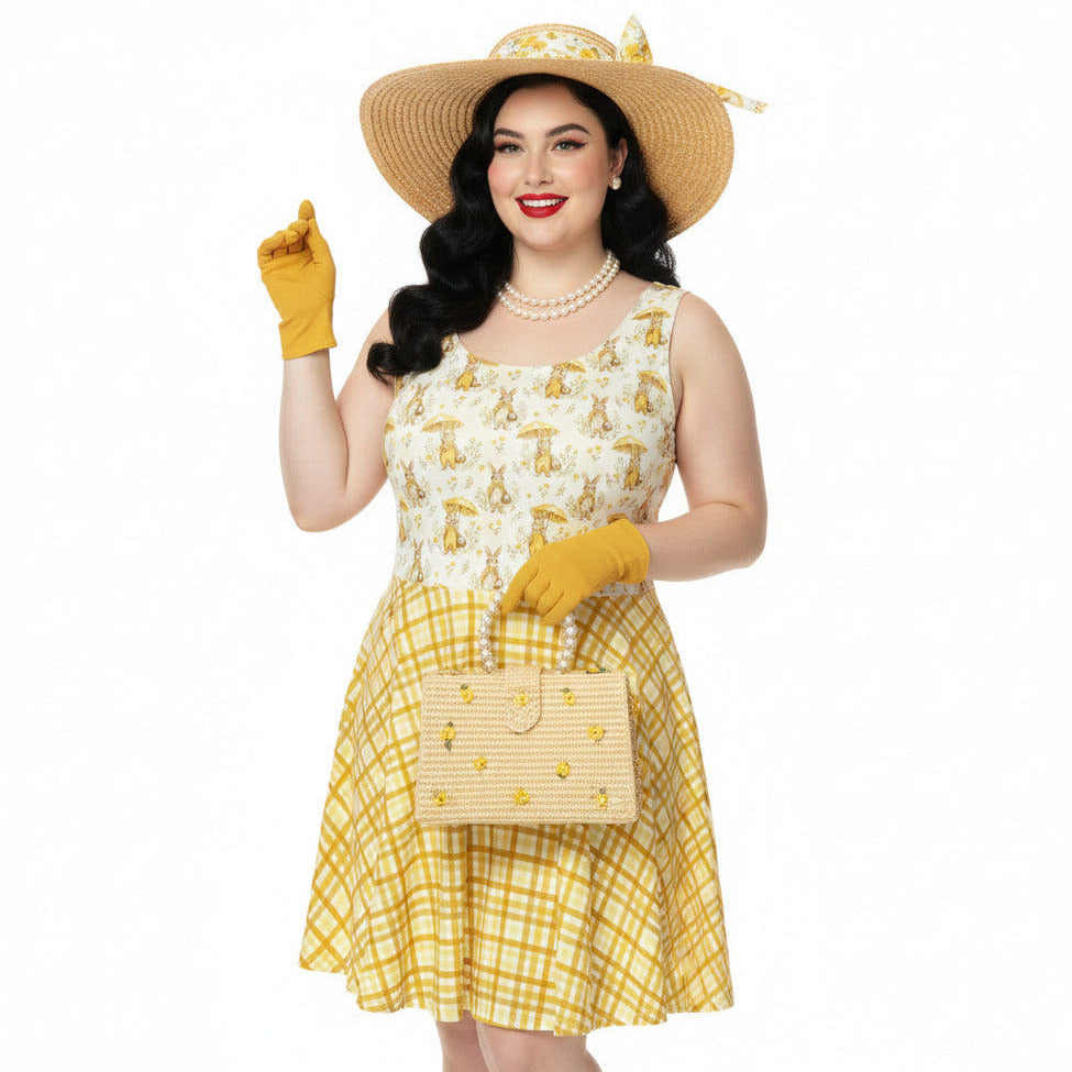 Plus size woman wearing a yellow gingham and Mr. Rabbit print 1950s vintage style fit and flare swing dress with straw hat.