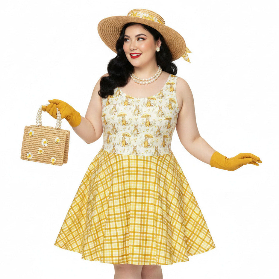 Plus size woman wearing a yellow gingham and Mr. Rabbit print 1950s vintage style fit and flare swing dress with straw hat.