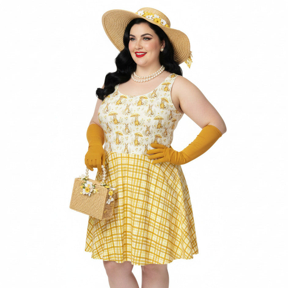 Plus size woman wearing a yellow gingham and Mr. Rabbit print 1950s vintage style fit and flare swing dress with straw hat.