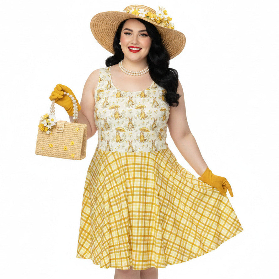 Plus size woman wearing a yellow gingham and Mr. Rabbit print 1950s vintage style fit and flare swing dress with straw hat.