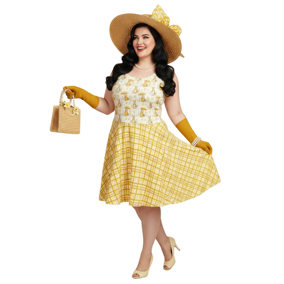 Plus size woman wearing a yellow gingham and Mr. Rabbit print 1950s vintage style fit and flare swing dress with straw hat.