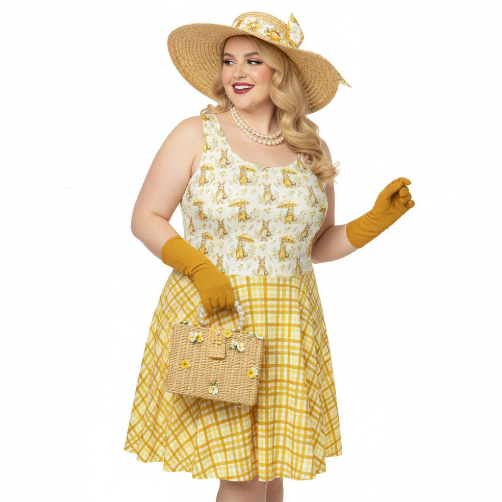 Plus size woman wearing a yellow gingham and Mr. Rabbit print 1950s vintage style fit and flare swing dress with straw hat.