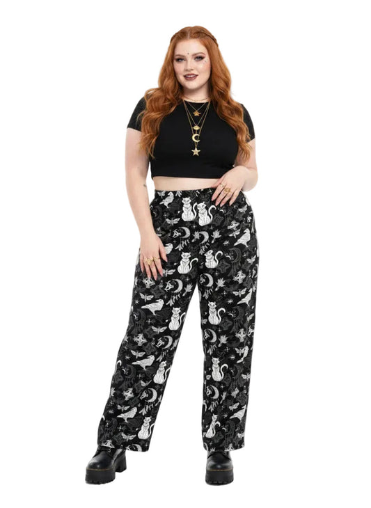 Woman wearing black wide-leg Whimsigoth lounge pants with white celestial cat and moon print.