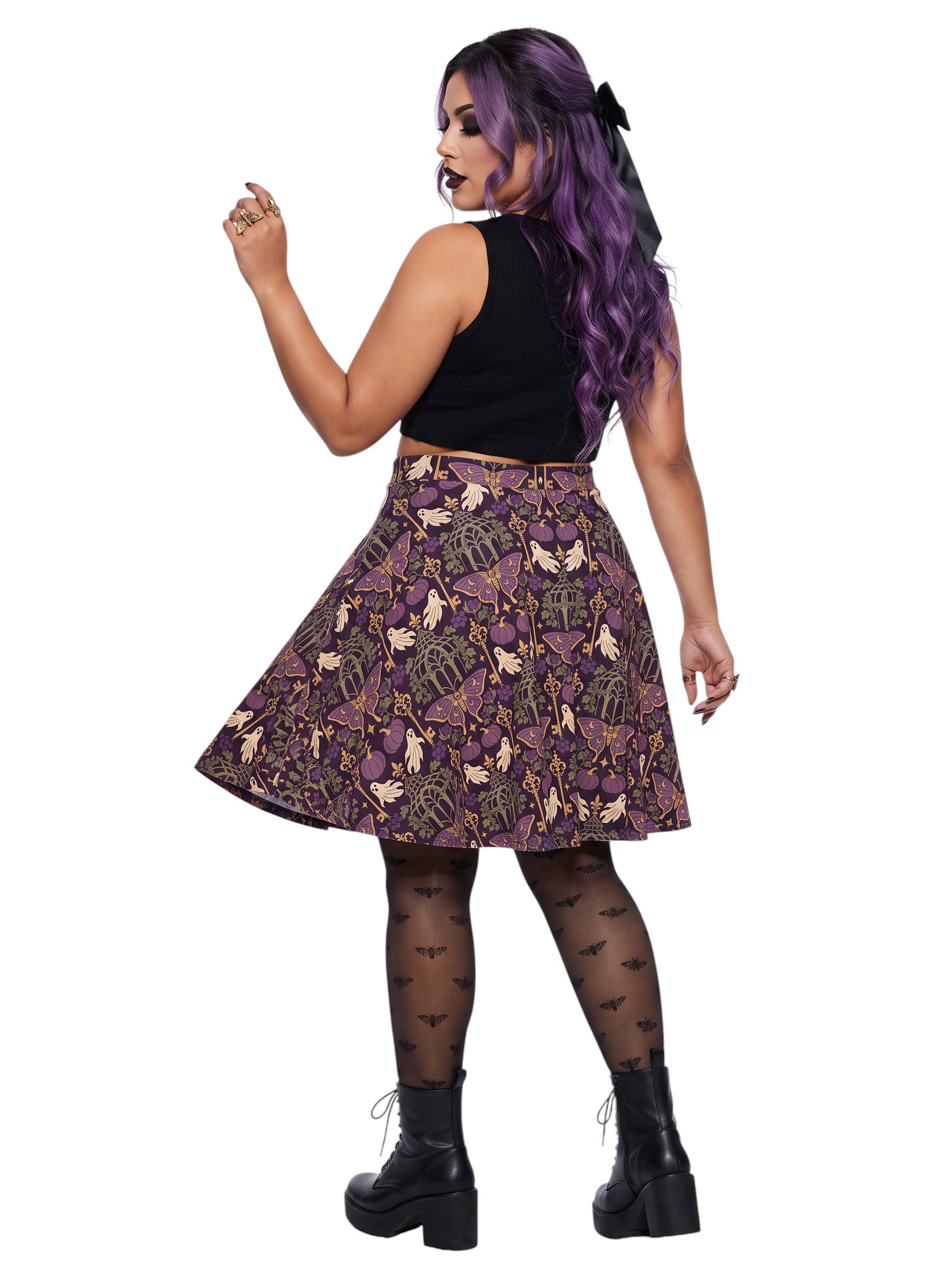 Woman wearing a purple Whimsigoth moth print goth flare skirt with black crop top and moth tights.
