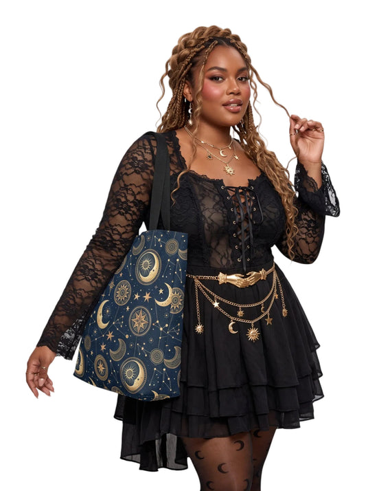 Plus size model in a black goth dress modeling a navy blue Whimsigoth sun and moon tote bag with gold celestial patterns.