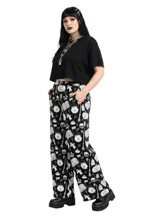 Woman wearing black and white witchy voodoo doll print wide leg lounge pants with side pockets.