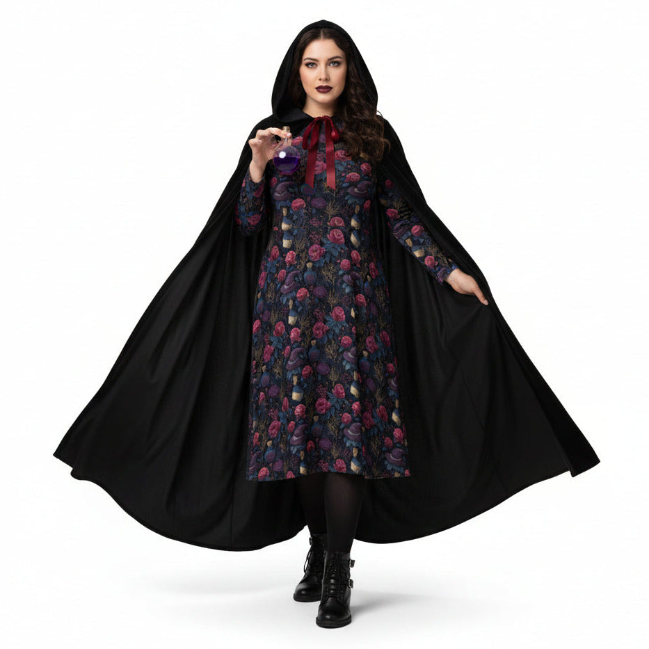 Woman wearing a floral dress with a black cape on a white background