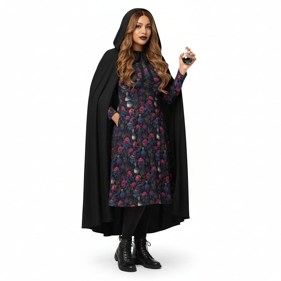 Woman wearing a black cape over a floral dress on a white background