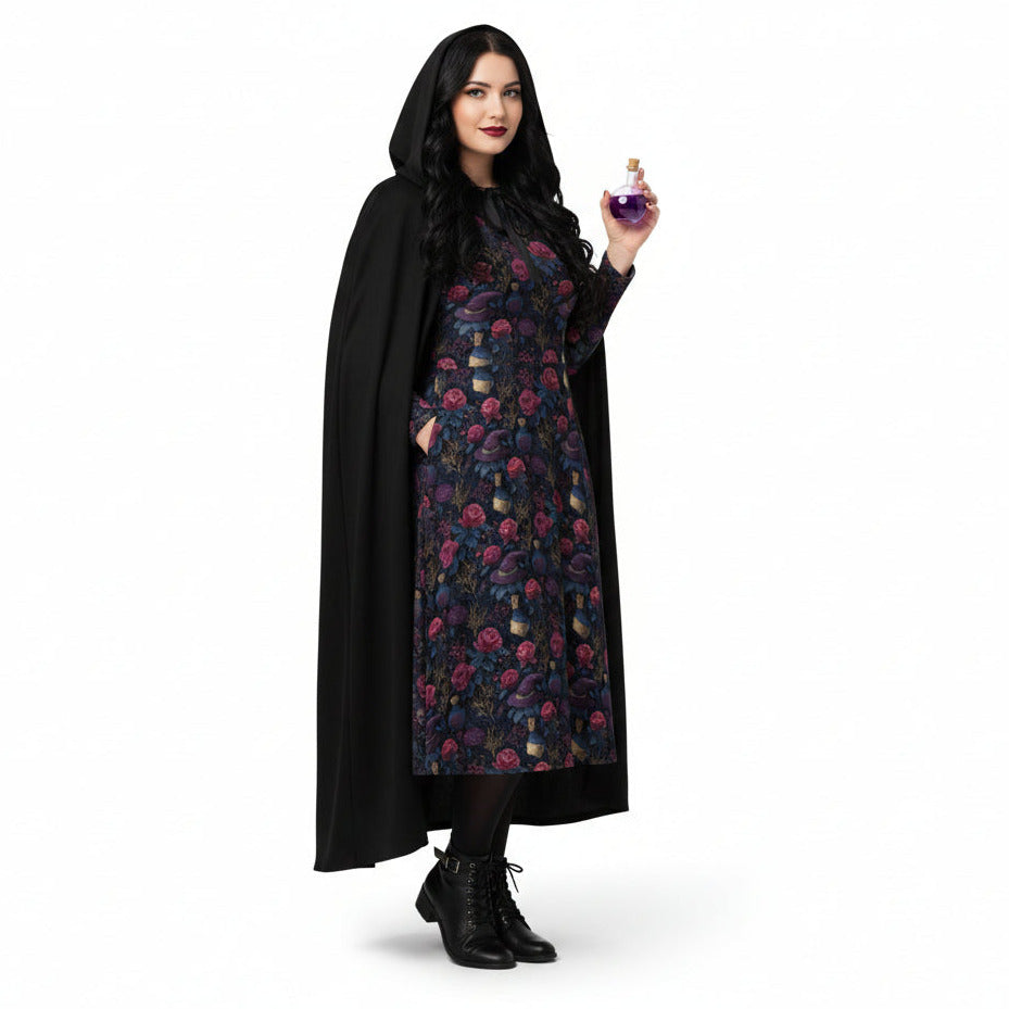 Woman wearing a black cape over a floral dress, holding a purple object on a white background