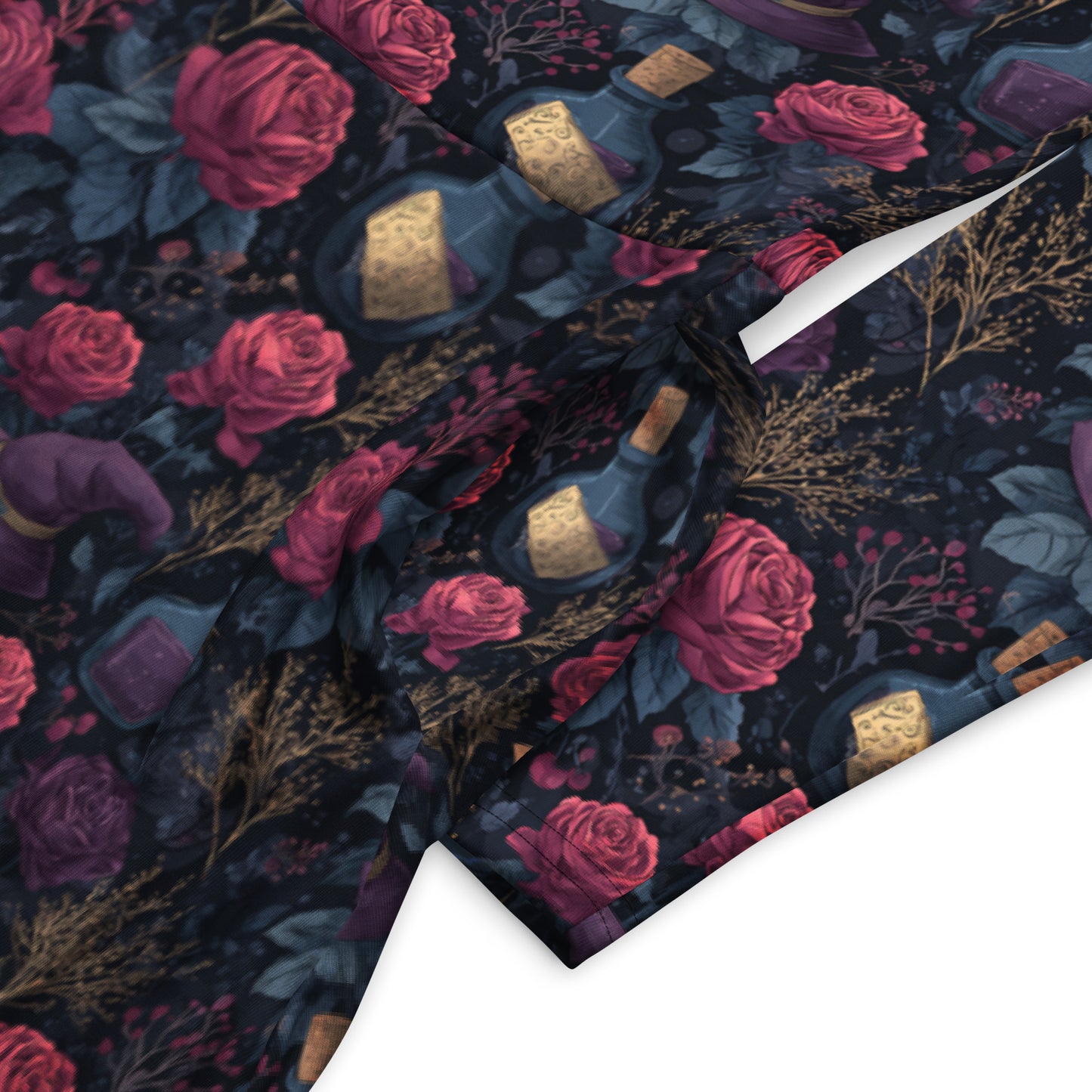 Patterned fabric with roses, bottles, and jewelry on a dark background